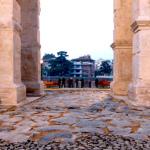 a stone walkway with pillars and people walking