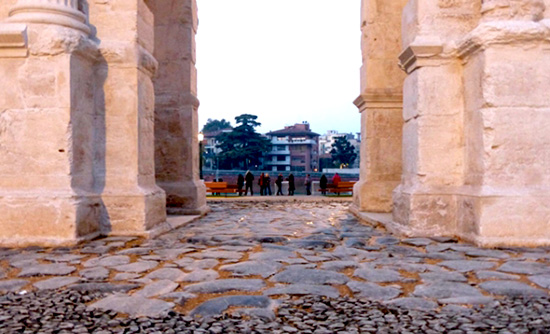 a stone walkway with pillars and people walking
