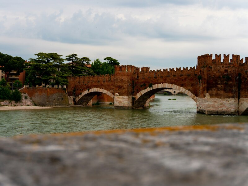 Ponte di Castelvecchio sul fiume Adige a Verona, con le caratteristiche mura merlate in mattoni rossi.